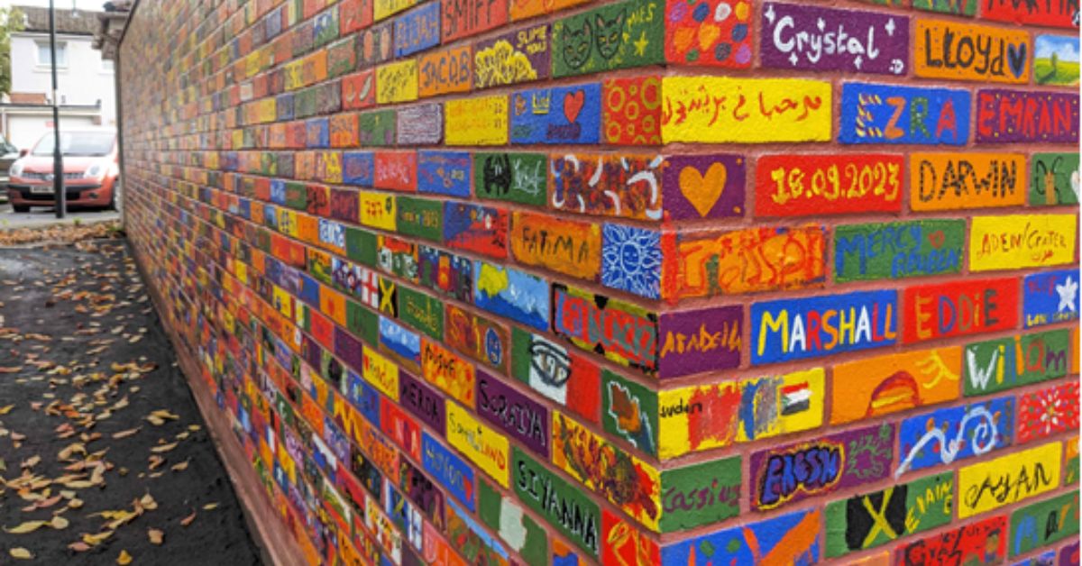 image shows a brick wall with each brick painted with colourful designs