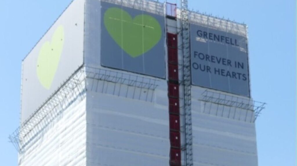 Image of Grenfell Tower with a banner reading: "Forever In Our Hearts"