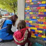 A mother and daughter painting designs on a brick wall