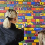 Two GCH staff painting designs on a brick wall